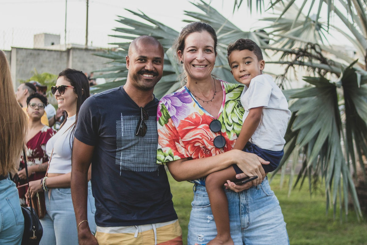 A smiling couple with their young son, standing together outdoors