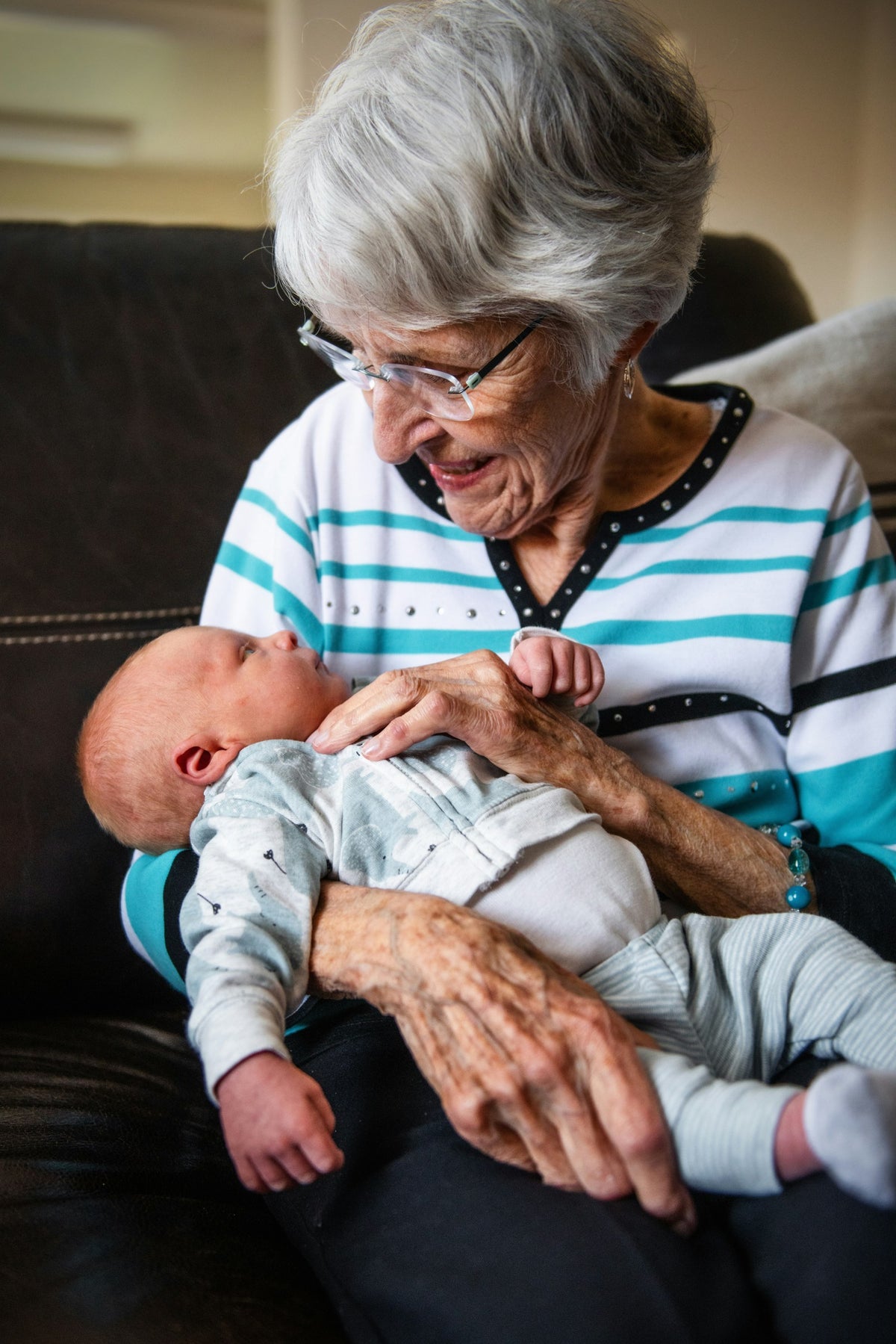 A grandmother smiling down at a newborn baby in her arms